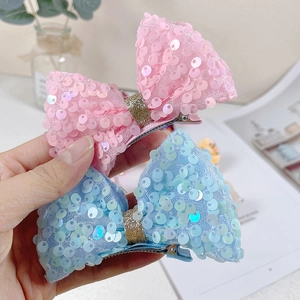 Detail of sequined mermaid bow hair clips in pink and blue mesh with metal duckbill clips