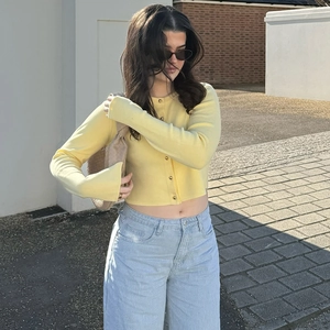 Gros plan détaillé du gilet en maille jaune montrant la texture et les boutons