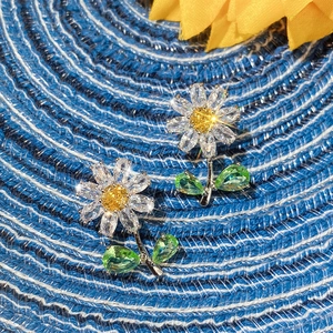 Macro detail of daisy flower earrings with white petals and yellow gemstone centers