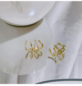 Macro detail of gold plated geometric earrings with zircon micro-pave on white reflective base