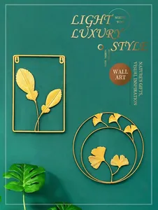 Detail of luxury gold metal wall art featuring feather and ginkgo leaf designs