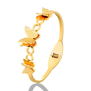 Detail of golden butterfly bangle featuring frosted wing texture and spring clasp