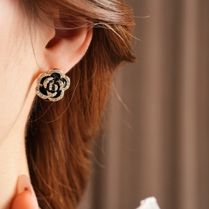 Close-up of elegant gold and black rose stud earring with crystal petals on model