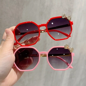 Detail view of kids' polygon sunglasses featuring a sparkling rhinestone bow on plastic frames