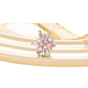 Silver flower earring with pink and white gems on a ceramic plate, elegant jewelry
