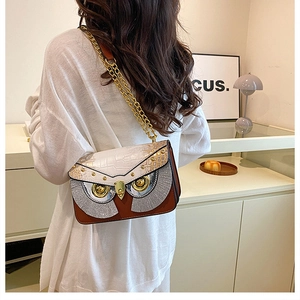 Détail du sac bandoulière en forme de hibou avec chaîne dorée et texture cuir patchwork