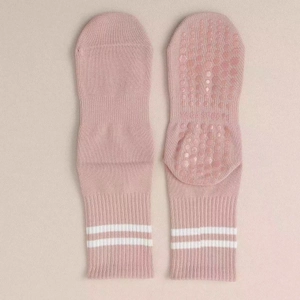 Close-up of pink yoga socks with white stripes and non-slip grippy dots on the sole