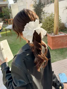 Detailed view of white embroidered lace scrunchie worn on a ponytail in outdoor setting