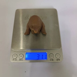 Macro detail showing a brown bear figurine being weighed on a digital scale for accuracy