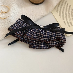 Macro detail of plaid bow hair clip with heart zircon on elegant white background
