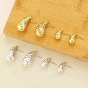 Detail of chunky C-shape croissant hoop earrings in gold and silver metal finishes