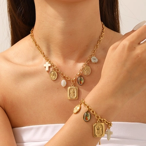 Detail of gold-plated necklace set with Virgin Mary and cross charms on model