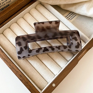 Detailed view of a square leopard tortoiseshell hair claw clip in a wooden jewelry box