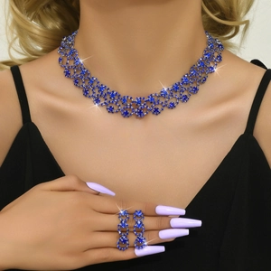 Detailed view of women's jewelry set with blue rhinestones necklace and ring on model