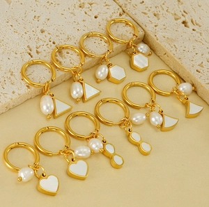 Détail de boucles d'oreilles en or 18K avec perles blanches et breloques nacre
