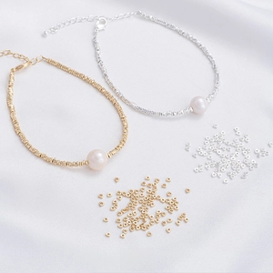 Detail of 14K gold filled and thick silver 2mm beads with a pearl on silk background