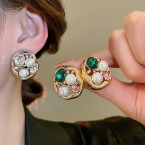Close-up of vintage irregular pearl earrings with rhinestones and colorful gemstones