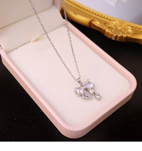 Gros plan d'un pendentif nœud argenté serti de zircons dans un écrin rose