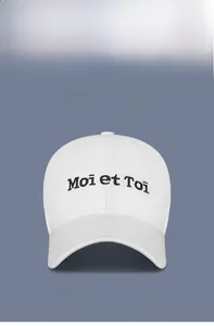 Detail of white cotton baseball cap with Moi et Toi embroidery and multi-color options