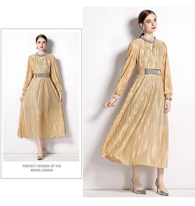 Detail of elegant gold pleated maxi dress with waist belt and long sleeves for women