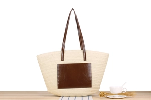 Macro detail of straw woven texture and brown leather pocket on beige tote bag
