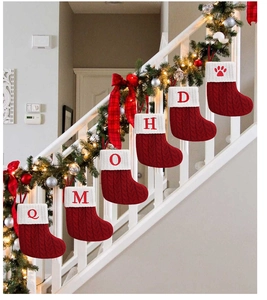 Close-up of red knit Christmas stockings with white fur cuffs and embroidered letters