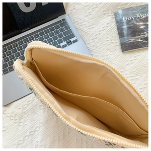 Detail view of the floral laptop sleeve interior with beige lining and storage pocket