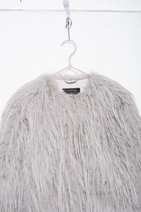 Detailed view of light gray faux fur coat with long fluffy texture and soft volume