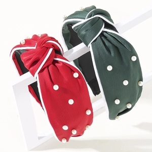 Detail of red and dark green knot headbands with white faux pearls and fabric texture