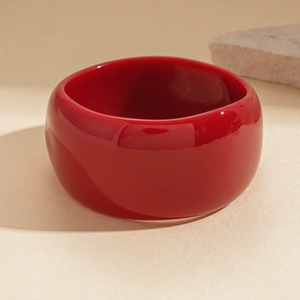 Macro detail of wide red acrylic resin bangle with a high-gloss minimalist finish