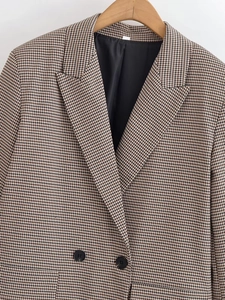 Détail d'un blazer à motif pied-de-poule avec boutons à double boutonnage et col