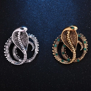 Detailed view of cobra snake brooches with silver and gold finishes featuring crystals