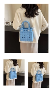 Detailed close-up of sky blue woven EVA beach bag with adjustable strap and top handles