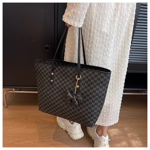 Detail shot of black tote bag with vintage monogram pattern and elegant bow charm accessory