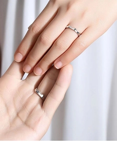 Close-up of artistic mountain pattern silver rings on hands for couples in love