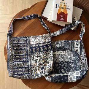 Close-up of bohemian linen shoulder bags with floral and paisley patterns on wooden table