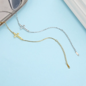 Flat lay of minimalist gold and silver cross necklaces on a light blue background