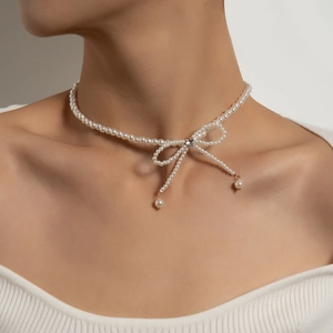 Elegant pearl choker necklace with a crystal bow pendant and tassels on a model