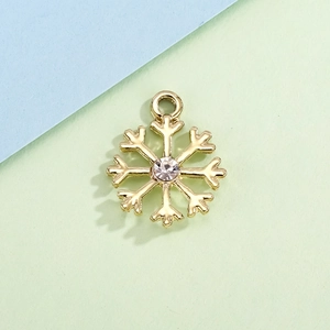 Detailed macro view of a golden snowflake pendant with a clear center rhinestone