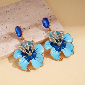 Detailed macro of vintage floral drop earrings with blue enamel and crystal accents