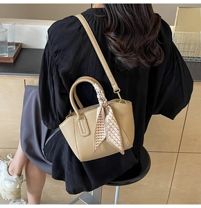 Close-up of beige lychee pattern bucket bag with decorative heart print handle silk scarf