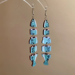 Detailed close-up of vintage wooden fish earrings with artistic teal floral patterns