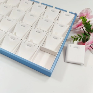 Light blue jewelry tray with white necklace display cards and floral background detail