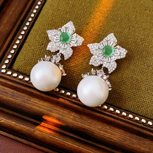 Détail macro de boucles d'oreilles perles vintage et pierres vertes sur velours vert foncé