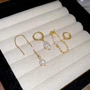 Four-piece gold pearl earring set featuring drops and studs on a white velvet display