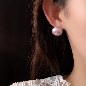 Close-up of elegant pink pearl earrings on model ear with delicate lace collar