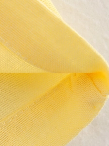 Macro shot showing high-quality yellow knit fabric texture and fine stitching details