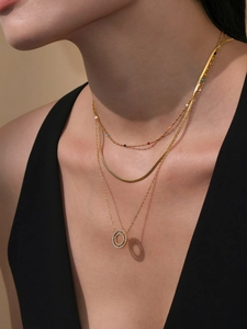Detail of layered gold stainless steel necklace with crystal pavé rings on female model