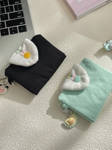 Pastel green and black coin purses with plush flaps and cute charms on desk