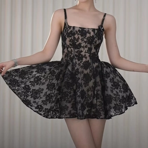 Détail d'une robe courte en dentelle noire montrant les motifs floraux et la jupe trapèze
